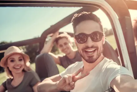 Glückliche Jugendliche bei Sonnenschein im Jeep unterwegs Berufsunfähigkeitsversicherung